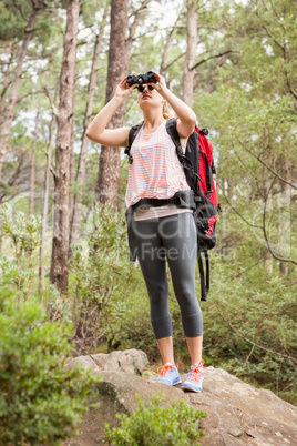 Blonde hiker looking through binoculars