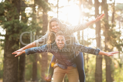 Smiling handsome man giving piggy back to his girlfriend