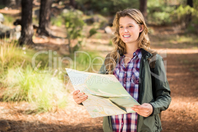 Pretty blonde hiker with map looking for path