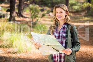 Pretty blonde hiker with map looking for path