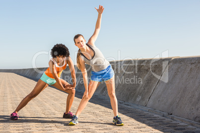 Two young woman stretching together