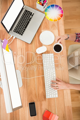 Casual designer working with computer and having coffee
