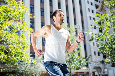 Handsome athlete jogging in front of buildings