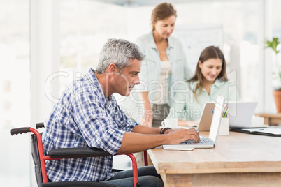 Casual businessman in wheelchair using laptop