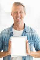 Smiling businessman showing up his tablet