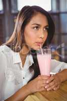 A beautiful woman drinking a pink milkshake
