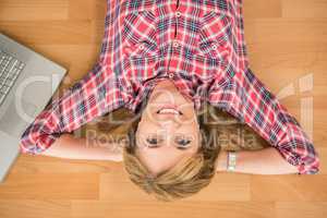 Smiling woman lying on floor next to laptop