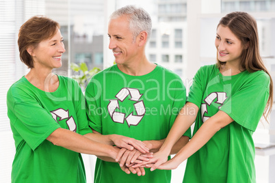 Smiling eco-minded colleagues putting hands together