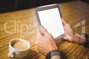Man drinking coffee and using tablet computer
