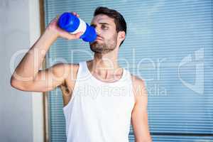 Handsome athlete drinking out of bottle