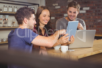 Smiling friends pointing and looking at tablet computer