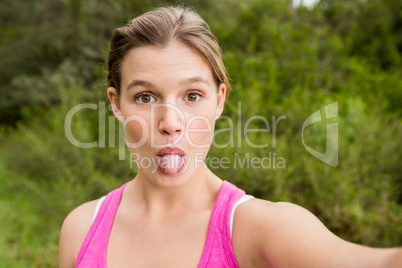 Pretty blonde athlete taking selfie with outstretched tongue