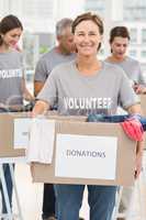 Smiling female volunteer carrying donation box