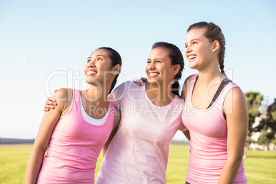 Three laughing women wearing pink for breast cancer