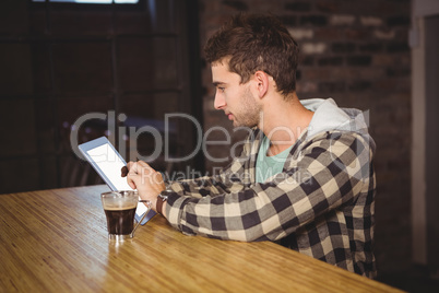 Hipster having coffee and using tablet computer