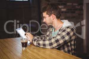 Hipster having coffee and using tablet computer