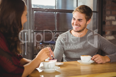 Handsome man enjoying cake and coffee with friend