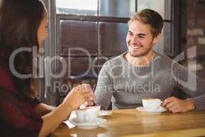 Handsome man enjoying cake and coffee with friend