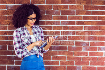 Attractive hipster leaning on wall and using tablet
