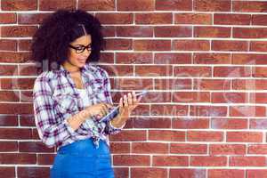 Attractive hipster leaning on wall and using tablet