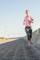 Focused sporty blonde jogging at promenade