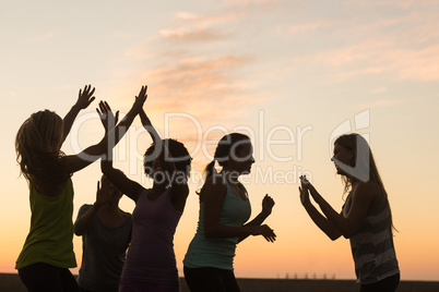 Happy sporty women cheering against sunset