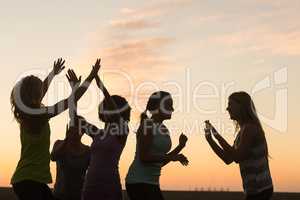 Happy sporty women cheering against sunset