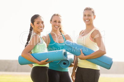 Smiling sporty women with exercise mats