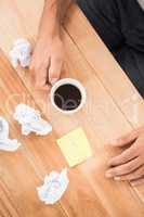 Hands holding coffee cup next to paper balls and sticky note