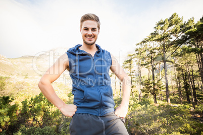 Young happy jogger standing on rock and looking at the camera