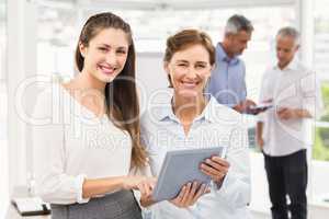 Smiling businesswomen using tablet in a meeting