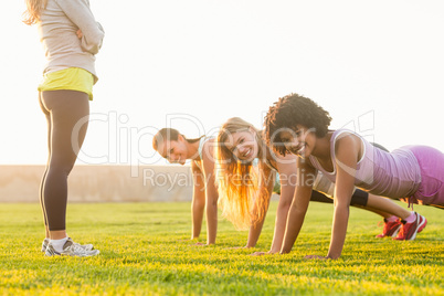 Smiling sporty women doing push ups during fitness class