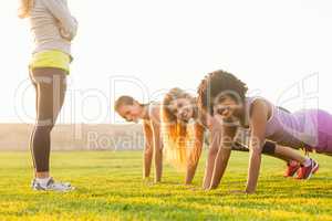 Smiling sporty women doing push ups during fitness class