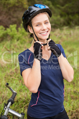 Smiling athletic blonde putting on helmet