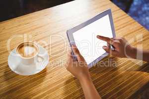 A businesswoman using a tablet and enjoying a coffee