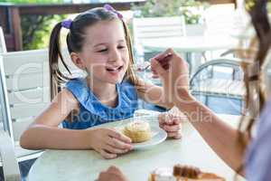 Mother and daughter enjoying cakes at cafe terrace