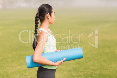Sporty woman holding exercise mat