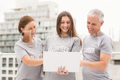 Smiling volunteers using laptop together