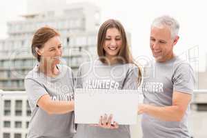 Smiling volunteers using laptop together