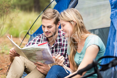 Young pretty hiker couple sitting in a tent looking at map