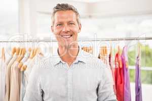 Smiling man in front of clothing rail