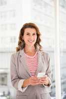 Smiling casual businesswoman holding smartphone