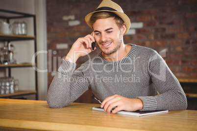 Handsome hipster phoning and holding pen