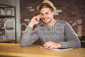 Handsome hipster phoning and holding pen