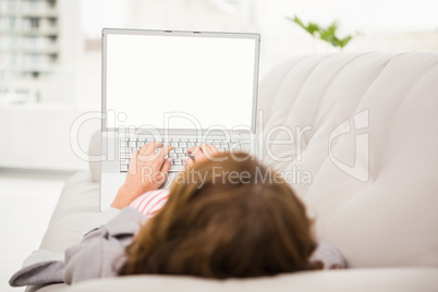 Casual businesswoman relaxing on couch with laptop