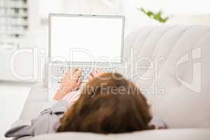 Casual businesswoman relaxing on couch with laptop