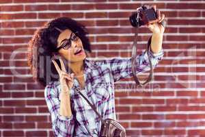Attractive hipster taking selfies with camera