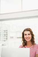 Smiling casual businesswoman working with laptop