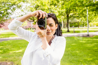 Beautiful brunette taking photo in the park