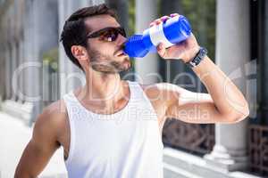 Handsome athlete with sunglasses drinking out of bottle